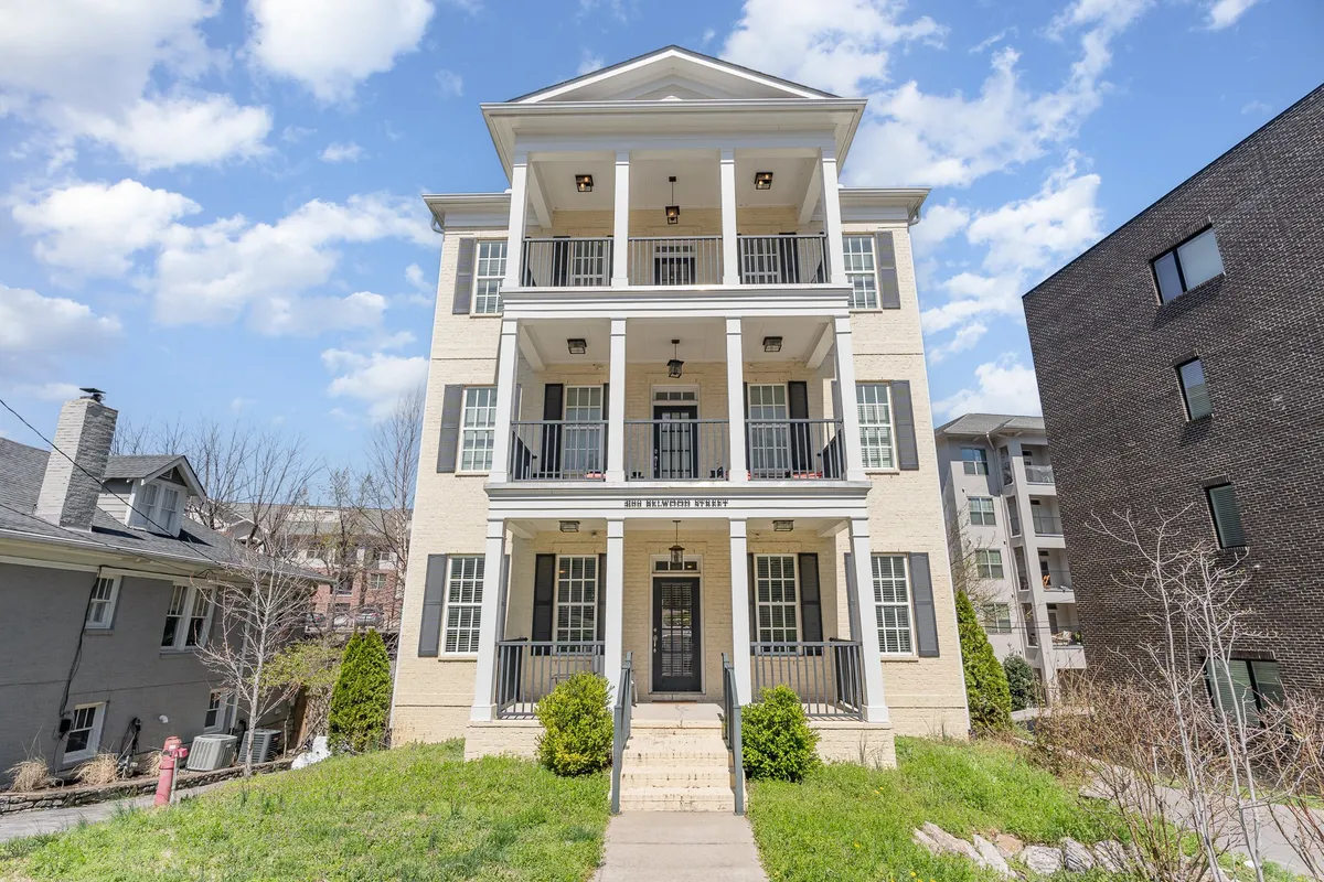 The welcoming front entrance of a residence featuring inviting porches, symmetrical windows, and a manicured front yard. The porch exudes friendliness and hints at space for gatherings and celebrations.