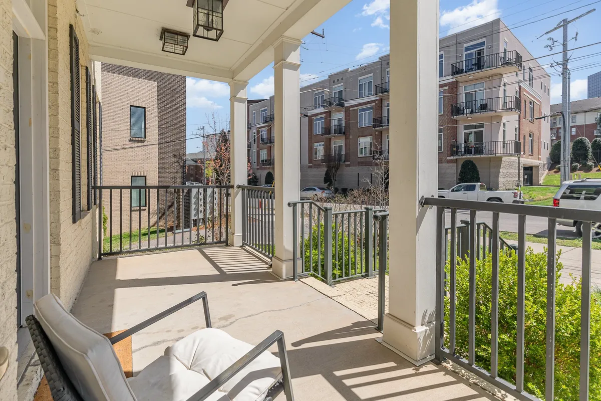 A welcoming porch area with railings and a comfortable seating set arranged for conversation. The outdoor area is positioned to catch soft natural light, ideal for socializing, relaxing, or reading outdoors.